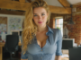 Jeune femme blonde aux yeux bleus avec chemise bleue entrouverte et regard séduisant, vue sur une application de discussion romantique intelligente