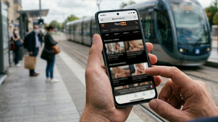 Main tenant un smartphone avec le site Pornhub ouvert montrant des recommandations de vidéos en France.