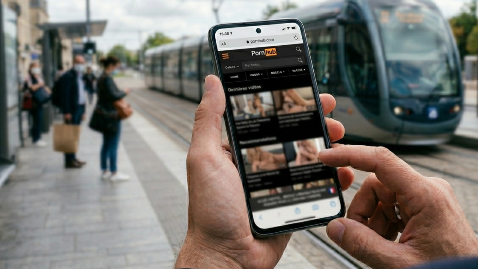 Main tenant un smartphone avec le site Pornhub ouvert montrant des recommandations de vidéos en France.