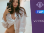 Jeune femme brune aux longs cheveux ondulés prenant un selfie devant un miroir, vêtue d'une chemise blanche entrouverte et regardant l'objectif avec une expression assurée.